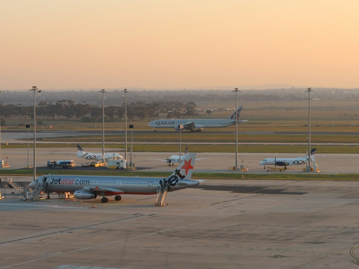 Airplanes are parked at an airport at sunset.